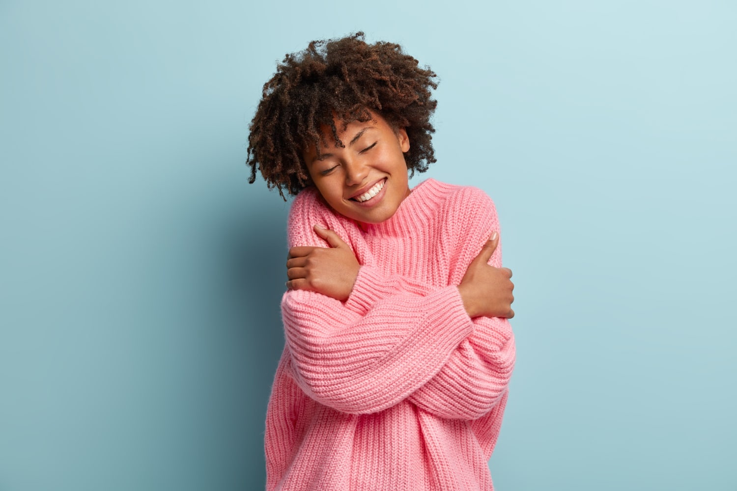 Femme heureuse portant un pull en laine rose